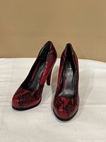 Front view of both pumps showing snake print pattern and toe scuffs