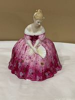 Front view of figurine showing gown pattern, fan and facial details