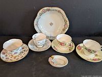 Group view of four teacup-saucer sets, floral plate and ashtray