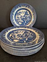 Stack of nine Churchill blue willow plates showing pattern and quantity