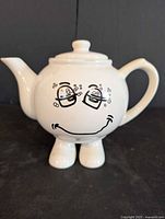 Front view showing face graphic, handle, spout, lid, and feet base