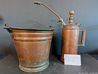 Copper pail alongside brass-copper sprayer full view