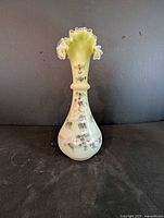 Full front view of custard glass vase showing shape, hand-painted decoration and ruffled rim