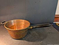 Overall view of copper saucepan with long handle