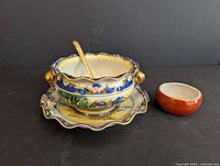 Bowl on saucer with spoon and small red bowl displayed