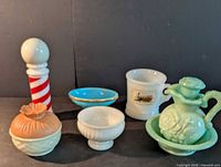 Group shot of six milk glass and colored glass pieces including barber pole, powder jar, jadeite cruet