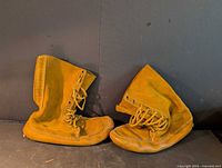 Pair of tan suede lace-up mukluk boots displayed side by side