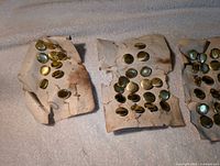 Three paper cards holding brass buttons showing overall quantity and condition