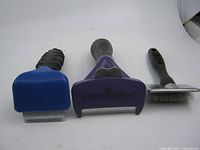 Three grooming tools standing upright showing heads and blades