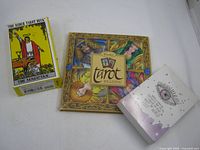 Three items: Rider Waite deck box, square Tarot Reading book, small eye-design book