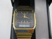 Close-up of watch face showing analog dial, LCD, gold-tone case and bracelet