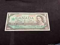 Front of Centennial $1 note showing portrait, serial number 7998935, signatures, maple leaf emblem