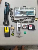 Overall lot view showing SnakeLight, rivet kit, chain with padlock, stud finder, tape measures, clamp, padlocks