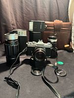 Overall lot showing camera with 50 mm lens attached, two Soligor lenses, flash, and case