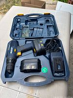 Drill kit open showing drill, two batteries, charger, bits and case