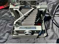 Overhead view of Polaroid 440 camera open with bellows extended showing interior and strap