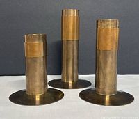 Three cylindrical brass and copper candleholders front view