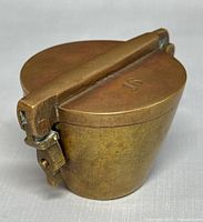 Closed brass nesting weight showing hinged lid and 16 stamp