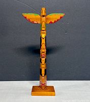 Full front view of totem pole showing wings and stacked figures