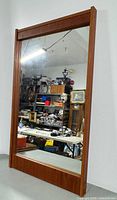 Full view of teak framed mirror leaning against wall