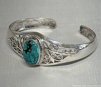 Front view of sterling silver cuff bracelet with turquoise stone and scroll cutouts