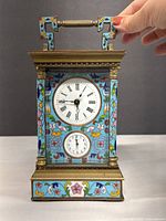 Front view showing main and alarm dials, floral cloisonné panels, brass handle