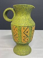Full side view of green textured footed pitcher with orange geometric band