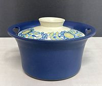 Angled view showing full casserole with lid on, blue exterior and patterned lid