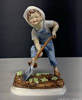 Front view of Royal Worcester figurine showing boy in blue overalls digging
