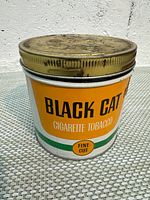 Front view of Black Cat Fine Cut cigarette tobacco tin with screw-top lid attached