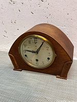 Front view of arched wood mantel clock showing dial and case