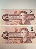 Front view of two 1986 Canadian $2 bills showing Queen Elizabeth II portrait and denomination