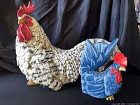 Large speckled rooster and small blue rooster side by side