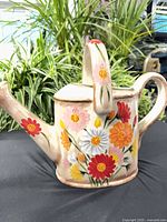 Full view of ceramic watering can front and side showing hand-painted flowers