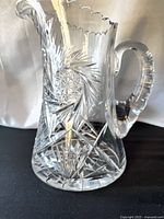 Full view of clear cut crystal pitcher showing pinwheel pattern and scalloped rim