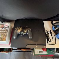 Top view of PS3 Slim console, DualShock 3 controller, GTA IV case and HDMI cables