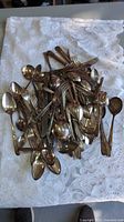Pile of mixed silver-plated flatware on fabric