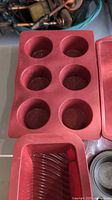red silicone 6-cup muffin pan alongside other bakeware