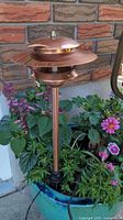 Copper low-voltage path light staked in planter