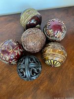 Six ornate decorative balls grouped on wooden surface