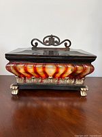 Front view showing amber resin panels, metal handle, claw feet