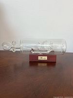 Full view of glass ship in bottle on wood stand