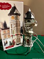 Front of ceramic clock tower alongside original box, showing brand and design