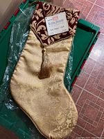 Full view of gold brocade stocking with red cuff and tag