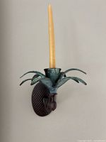 Full view of metal pineapple wall sconce with taper candle inserted