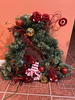 Front view of triangular wreath with red and gold decorations