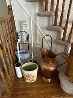 Group shot of all items at stair landing including copper ewer, waste baskets, plungers, holders