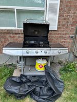 Front view of Charmglow gas BBQ grill with cover draped on ground