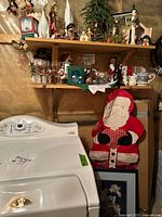 Shelf with various Christmas decorations and quilted Santa wall hanging