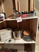 Overall view showing bread maker, stock pot, glassware stack, roasting pan on shelf